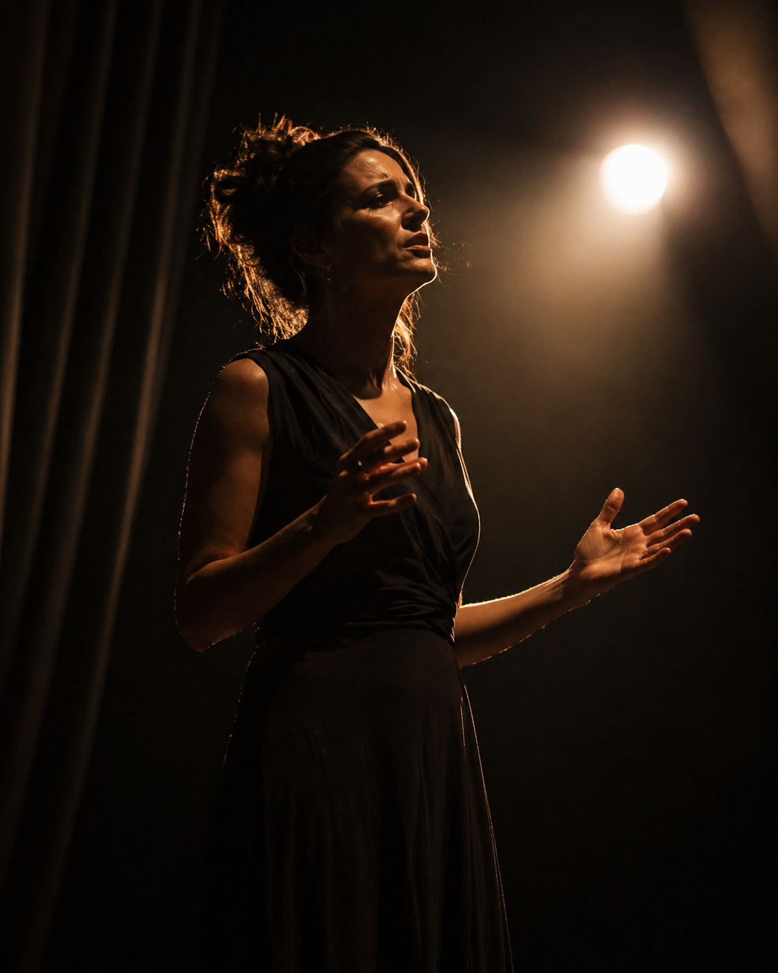 Donna sul palco in abito scuro – luce teatrale ambrata